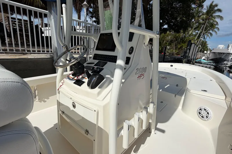 Slide: The Image of 2022 Pathfinder 2600 HPS boat interior with steering console and seating, docked near palm trees. - 34