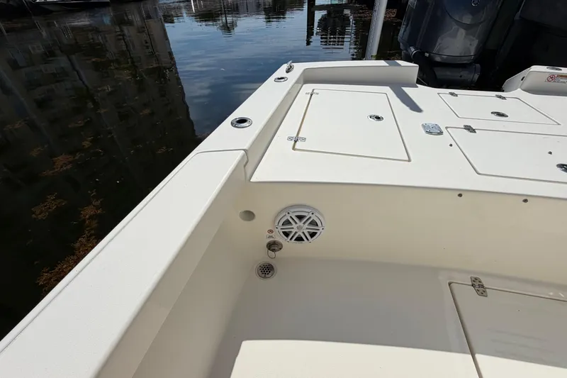 Slide: The Image of 2022 Pathfinder 2600 HPS boat interior with storage compartments and speaker, docked by the water. - 39