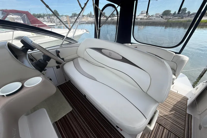 Slide: The Image of 1998 Four Winns 258 Vista boat interior with white seating and steering wheel, docked by the water. - 12