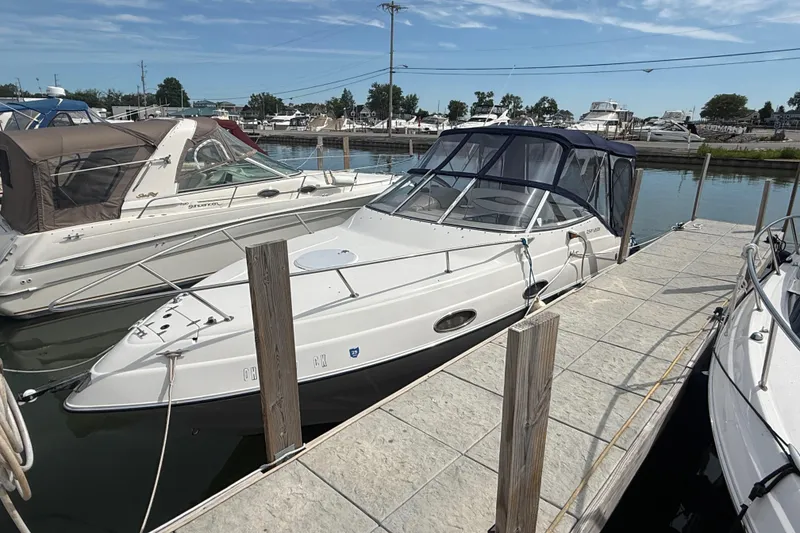 Slide: The Image of 1998 Four Winns 258 Vista boat docked at marina, featuring sleek design and canopy. - 2
