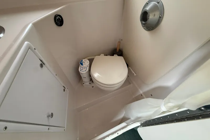 Slide: The Image of 1998 Four Winns 258 Vista boat bathroom with compact toilet and storage cabinet. - 24