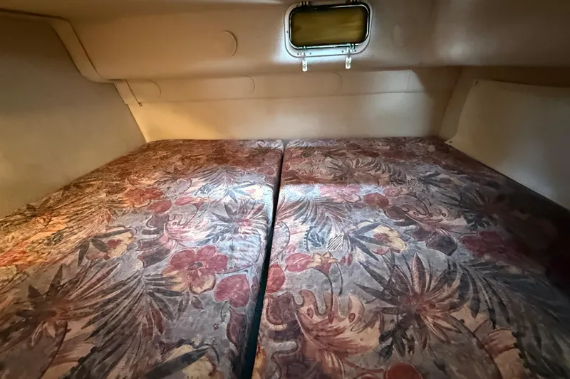 Slide: The Image of 1998 Four Winns 258 Vista cabin interior with floral-patterned bedding and small window. - 25