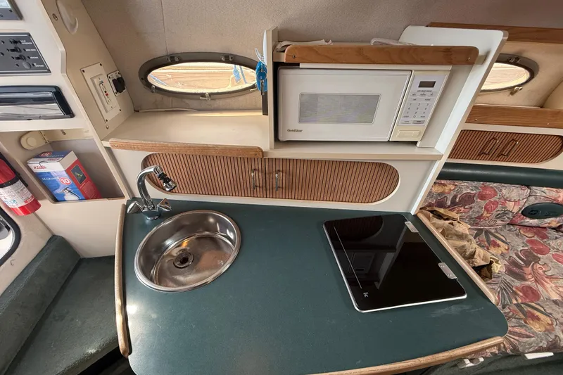 Slide: The Image of 1998 Four Winns 258 Vista boat interior with kitchenette, sink, microwave, and seating area. - 28