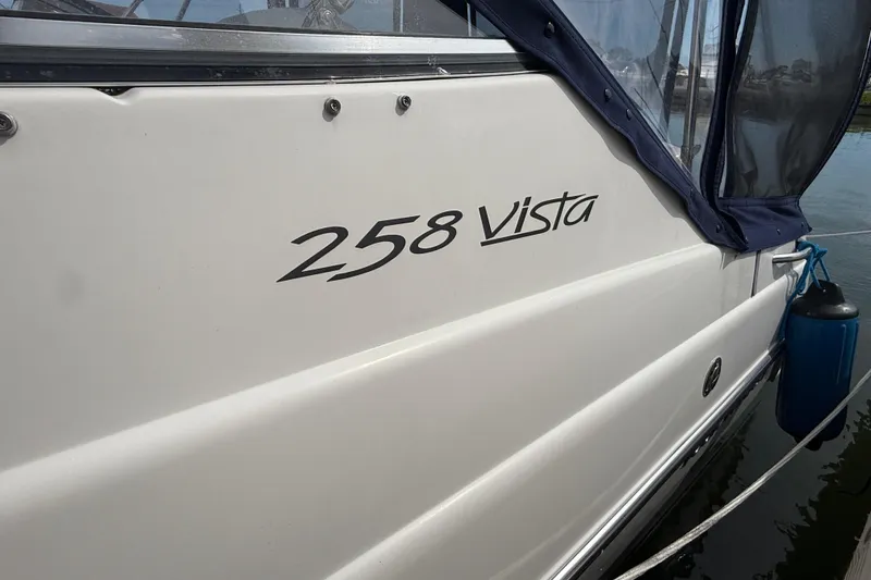Slide: The Image of 1998 Four Winns 258 Vista boat with blue canopy and docked on water. - 3