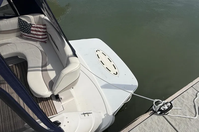 Slide: The Image of 1998 Four Winns 258 Vista boat with American flag pillow, docked on calm water. - 5
