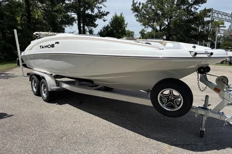 Slide: The Image of 2026 Tahoe 2150 boat on trailer, parked outdoors, surrounded by trees. - 1