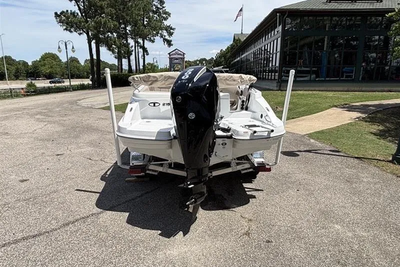 Slide: The Image of 2026 Tahoe 2150 boat with outboard motor parked outdoors. - 2