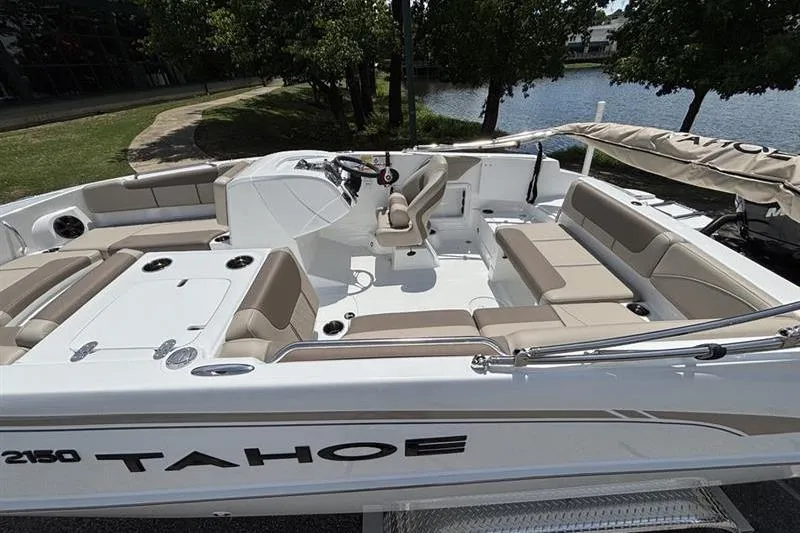 Slide: The Image of 2026 Tahoe 2150 boat with spacious seating, docked near a serene lake. - 3
