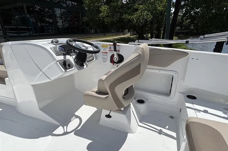 Slide: The Image of 2026 Tahoe 2150 boat interior with steering wheel and seating, near a serene water body. - 8
