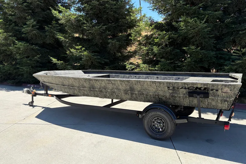Slide: The Image of 2026 Tracker Grizzly 1860 Utility boat on trailer, parked outdoors near trees. - 4