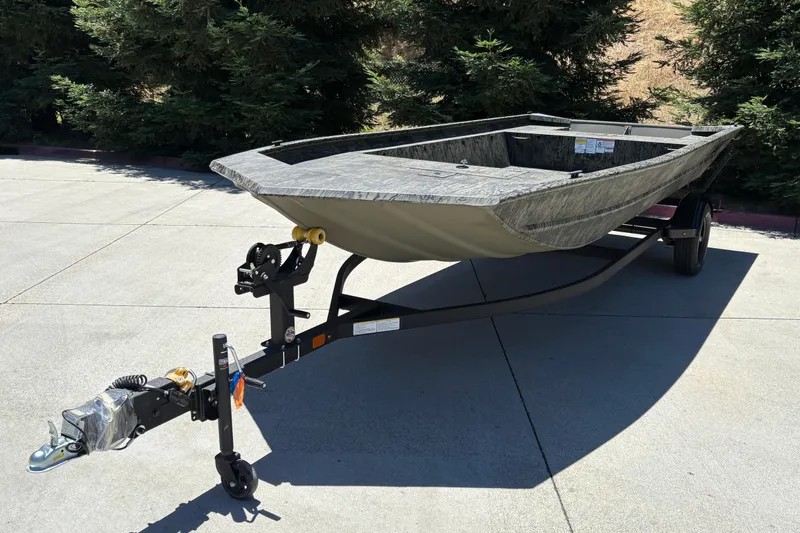 Slide: The Image of 2026 Tracker Grizzly 1860 Utility boat on trailer, parked on concrete driveway. - 8