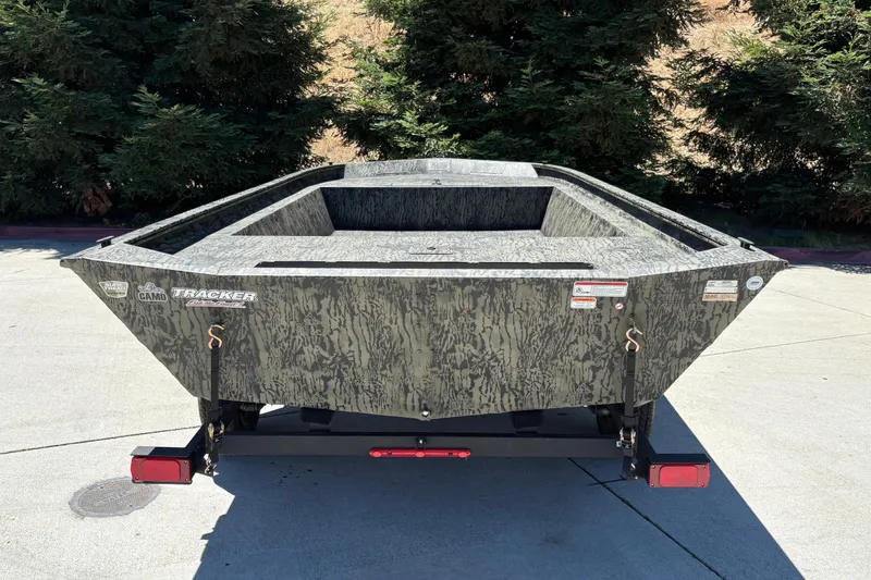 Slide: The Image of 2026 Tracker Grizzly 1860 Utility boat with camouflage design, parked outdoors. - 6
