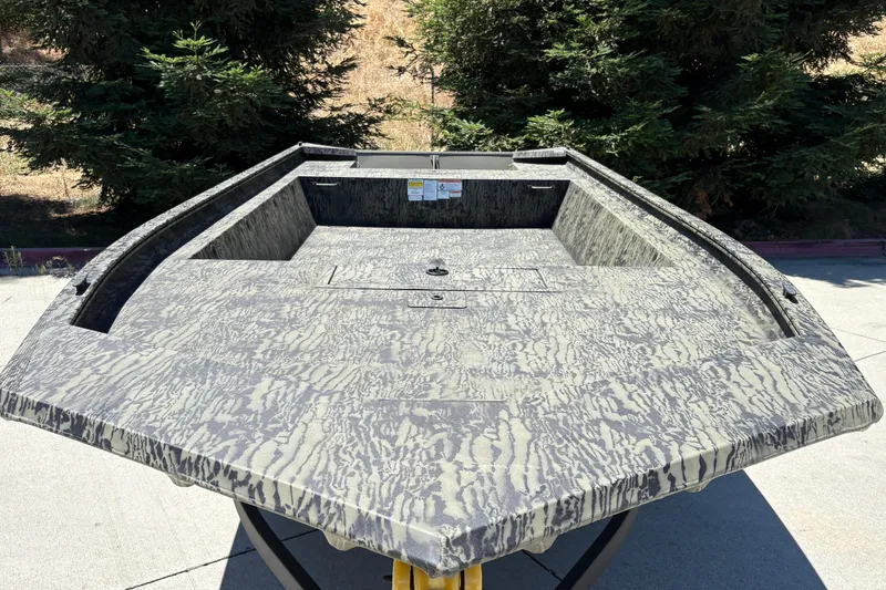 Slide: The Image of 2026 Tracker Grizzly 1860 Utility boat with camouflage pattern, parked outdoors. - 10