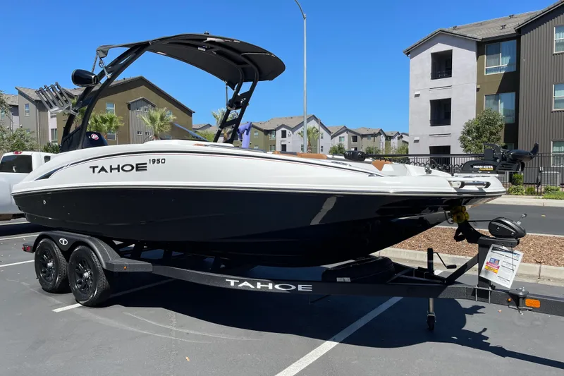Slide: The Image of 2026 Tahoe 1950 boat on trailer in urban setting, sunny day. - 2