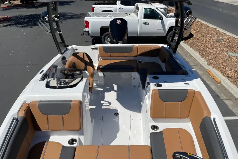 Slide: The Image of 2026 Tahoe 1950 boat interior with tan and gray seating, parked near white trucks. - 15
