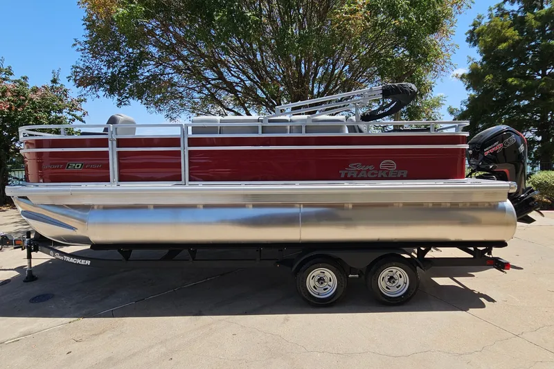The Image of 2026 Sun Tracker SportFish 20 DLX pontoon boat on trailer, parked outdoors. - 0