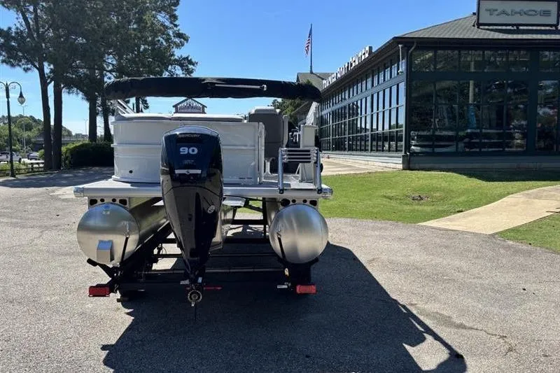 Slide: The Image of 2026 Sun Tracker Party Barge 20 DLX pontoon boat with 90 HP engine, parked outdoors. - 2