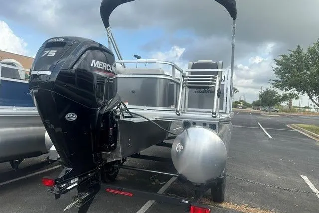 Slide: The Image of 2026 Sun Tracker Bass Buggy 18 DLX pontoon boat with Mercury 75 engine in parking lot. - 2
