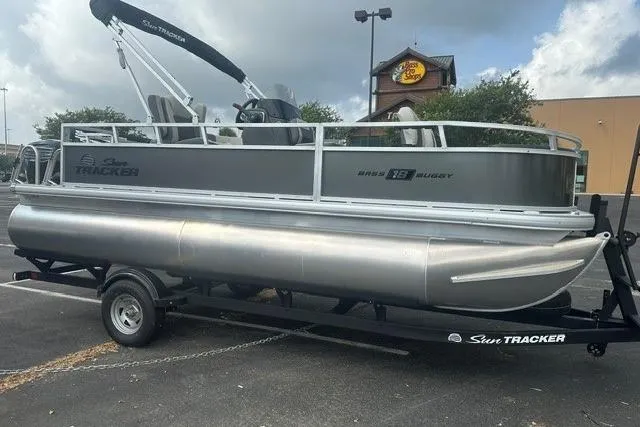 The Image of 2026 Sun Tracker Bass Buggy 18 DLX pontoon boat on trailer in parking lot. - 0