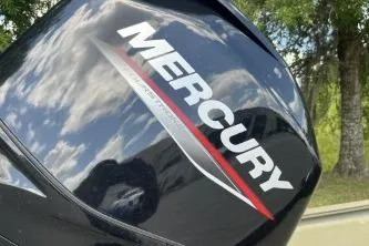 Slide: The Image of 2026 Tracker Grizzly 1648 SC with Mercury engine, reflecting sky and trees. - 6