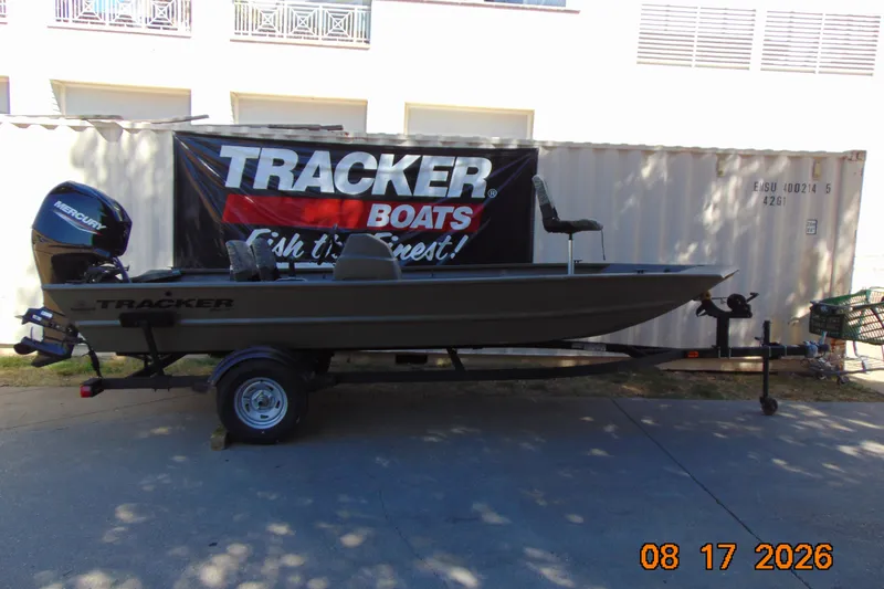 Slide: The Image of 2026 Tracker Grizzly 1754 SC boat on trailer, displayed outdoors with promotional banner. - 16