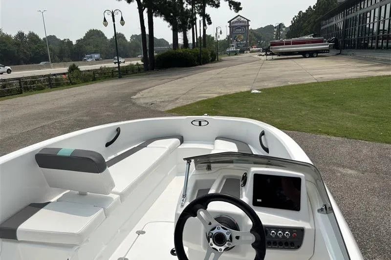 Slide: The Image of 2026 Tahoe T16 boat interior with steering wheel and seating, parked outdoors. - 14