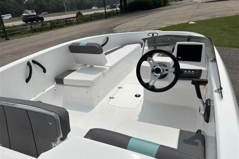 Slide: The Image of 2026 Tahoe T16 boat interior with modern steering and seating, parked near a highway. - 11