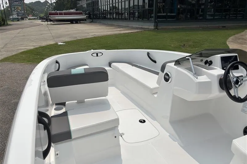 Slide: The Image of 2026 Tahoe T16 boat interior with seating and steering wheel, parked outdoors. - 9