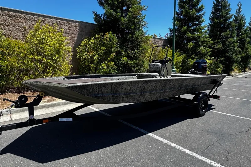 Slide: The Image of 2026 Tracker Grizzly 1860 CC boat on trailer in parking lot, surrounded by trees. - 4