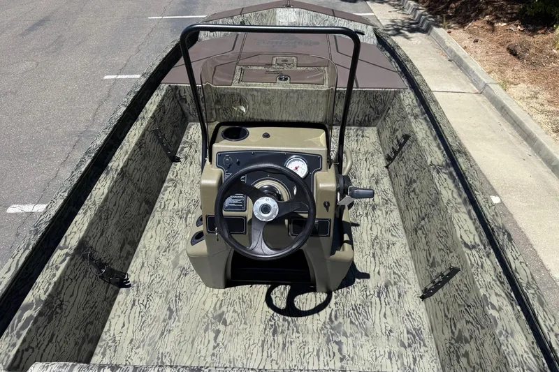Slide: The Image of 2026 Tracker Grizzly 1860 CC boat interior with camouflage design and steering console. - 10