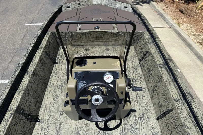 Slide: The Image of 2026 Tracker Grizzly 1860 CC boat interior with steering console and camouflage design. - 5