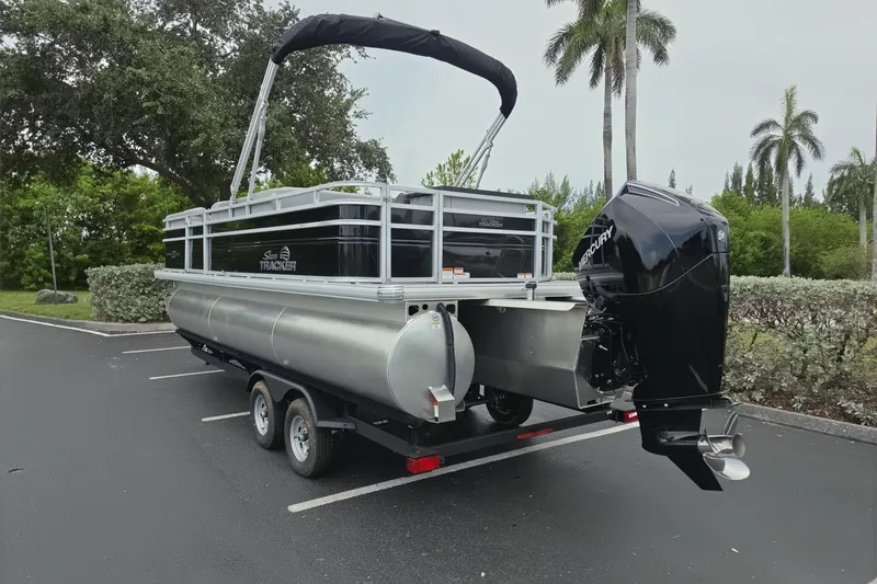 Slide: The Image of 2026 Sun Tracker SportFish 22 XP3 pontoon boat with Mercury outboard motor in a parking lot. - 15