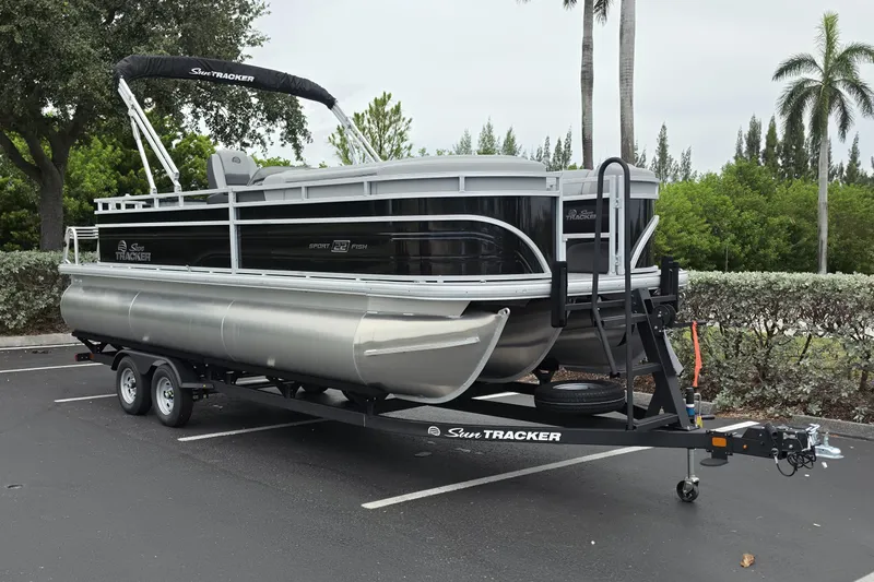 Slide: The Image of 2026 Sun Tracker SportFish 22 XP3 pontoon boat on trailer in parking lot. - 2