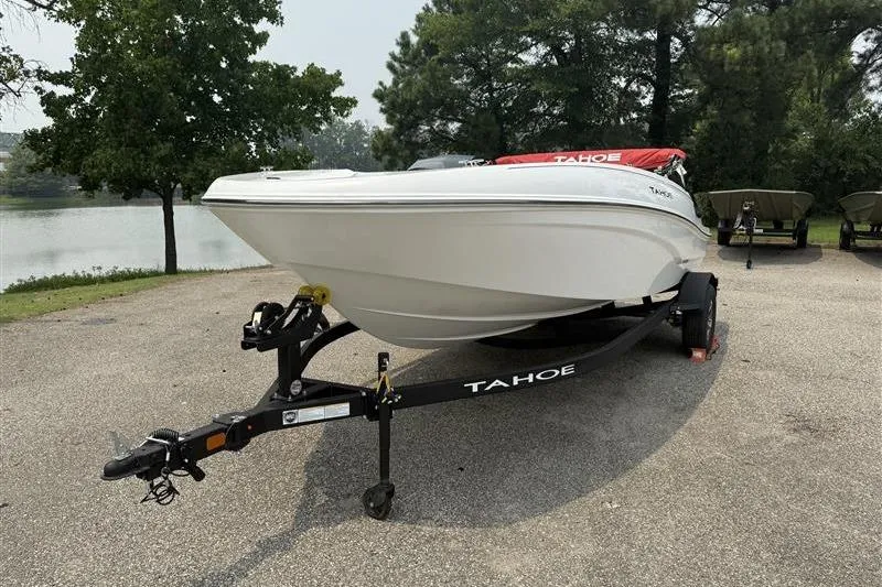 Slide: The Image of 2026 Tahoe T18 boat on trailer, parked near a scenic lake with trees. - 1