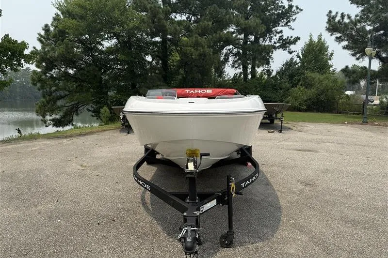Slide: The Image of 2026 Tahoe T18 boat on trailer, parked near a scenic lake with trees in the background. - 2