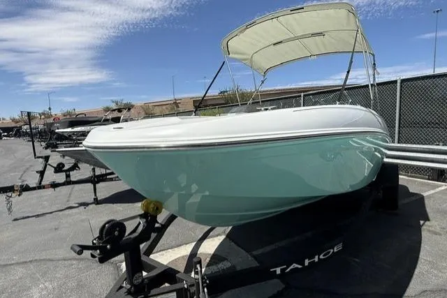 Slide: The Image of 2026 Tahoe T18 boat on trailer with canopy, parked outdoors under blue sky. - 2