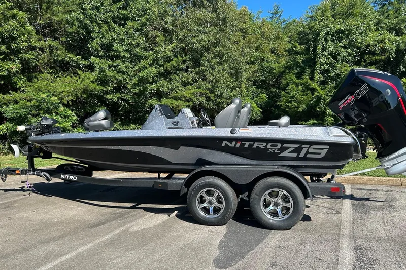 The Image of 2026 Nitro Z19 XL Pro boat on trailer, parked outdoors with lush greenery background. - 0