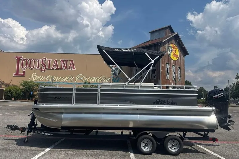 Slide: The Image of 2026 Sun Tracker Fishin' Barge 20 DLX pontoon boat parked at Louisiana Sportsman's Paradise. - 2