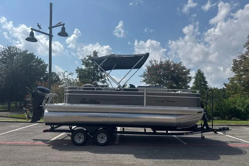 The Image of 2026 Sun Tracker Fishin' Barge 20 DLX pontoon boat on trailer, parked outdoors. - 0