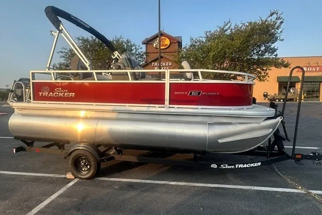 The Image of 2026 Sun Tracker Bass Buggy 16 XL Select pontoon boat on trailer in parking lot. - 0