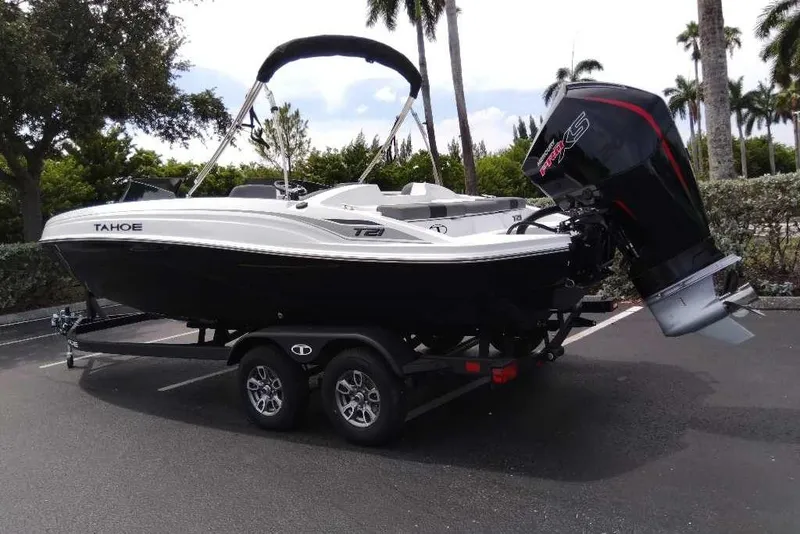 Slide: The Image of 2026 Tahoe T21 boat on trailer, parked outdoors with trees in background. - 11