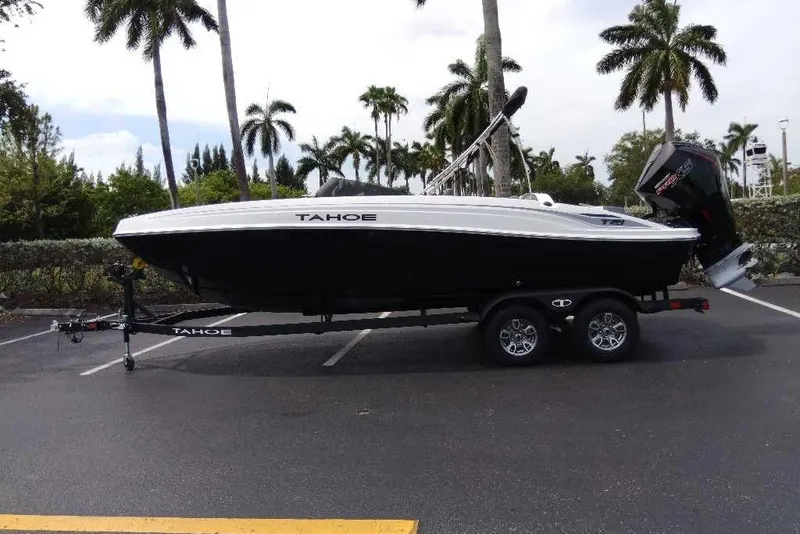 Slide: The Image of 2026 Tahoe T21 boat on trailer, parked under palm trees in a sunny setting. - 2
