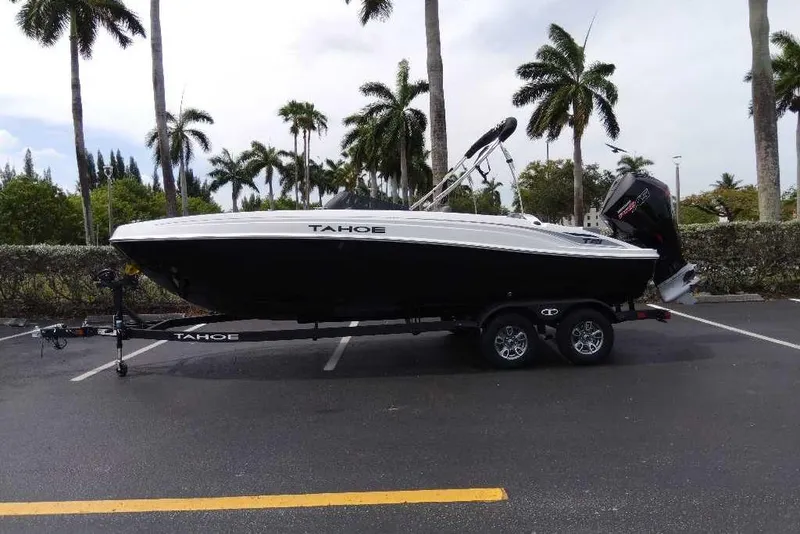 The Image of 2026 Tahoe T21 boat on trailer, parked under palm trees in a lot. - 0