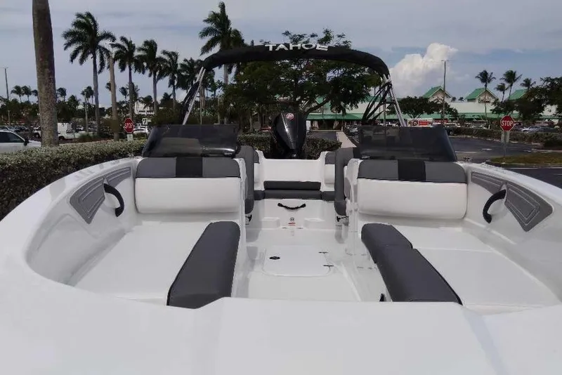 Slide: The Image of 2026 Tahoe T21 boat with sleek seating, parked near palm trees and a shopping area. - 5