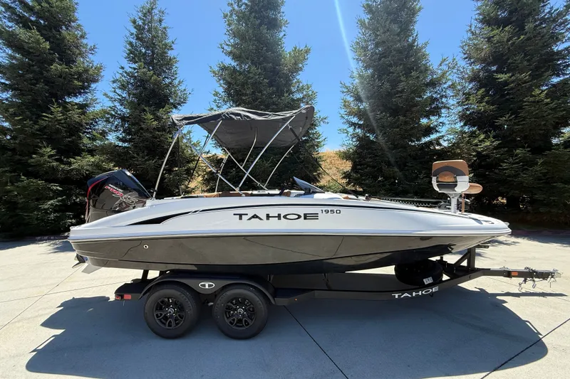 Slide: The Image of 2026 Tahoe 1950 boat on trailer, parked outdoors with trees in background. - 1