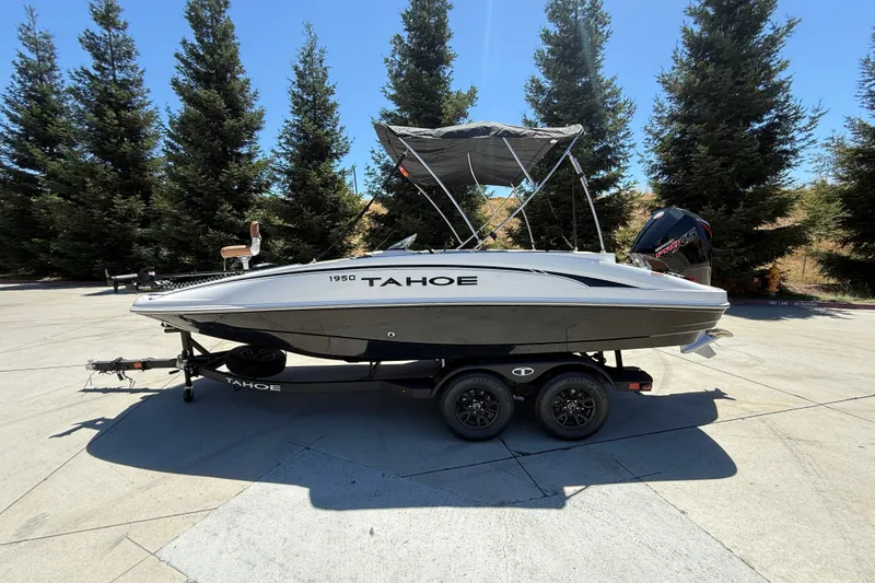 The Image of 2026 Tahoe 1950 boat on trailer, parked outdoors with trees in background. - 0