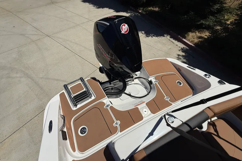 Slide: The Image of 2026 Tahoe 1950 boat with outboard motor and brown deck, parked on concrete. - 16