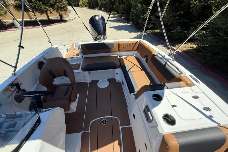 Slide: The Image of 2026 Tahoe 1950 boat interior with brown and black seating, steering console, and cup holders. - 10