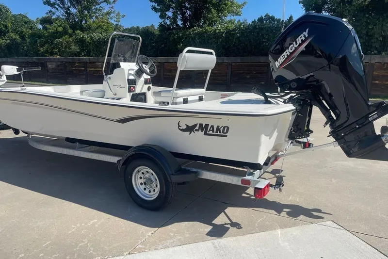 Slide: The Image of 2026 Mako Pro Skiff 17 CC boat with Mercury engine on trailer, parked outdoors. - 4