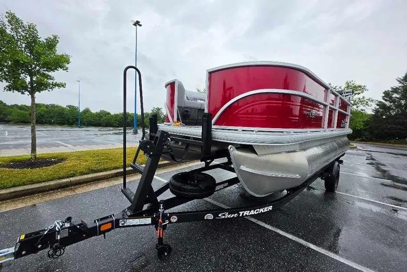 The Image of 2026 Sun Tracker Party Barge 18 DLX pontoon boat on trailer in parking lot. - 0